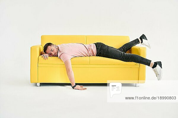 Lustige frustriert erschöpft Mann schläft auf Sofa über weißem Hintergrund. Ruhe  überarbeitetes Konzept