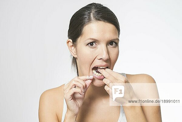 Frau  die ihre Zähne mit Zahnseide reinigt  um Speisereste und Bakterien zwischen den Zähnen zu entfernen und so Karies vorzubeugen
