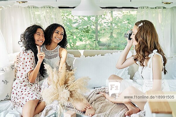 Schöne Frau macht Foto von ihren multiethnischen Freunden im Wohnmobil während ihrer Sommerreise. Mädchen haben Spaß