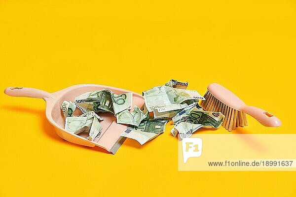 Kreative Layout mit Kehrschaufel  Hand Besen und zerknittert Geld Dollarscheine auf gelbem Hintergrund. Finanzen  Korruption  kriminelle Aktivität Konzept