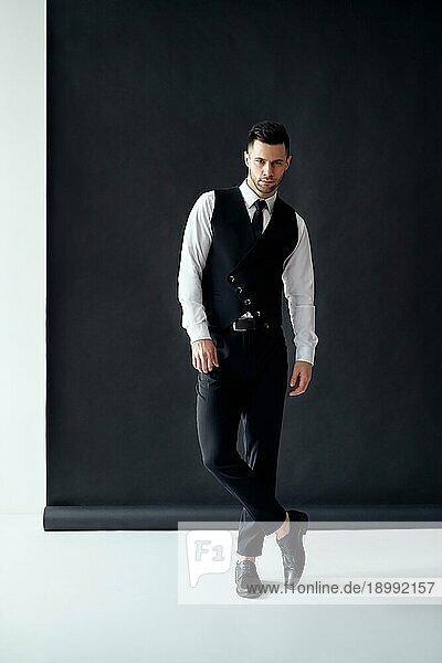 Full Length Porträt von gut aussehend eleganten Mann posiert auf schwarzem und weißem Hintergrund. Mode Konzept