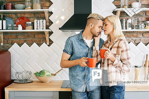 Junge glückliche Paar in der Liebe trinken Kaffee am Morgen umarmt in der Küche zu Hause. Beziehung  Familie Konzept