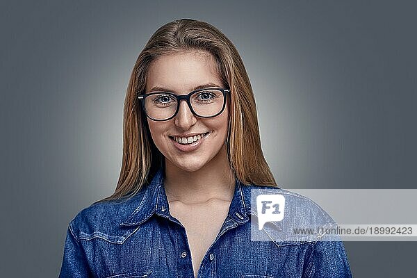 Attraktive  stilvolle blonde Frau mit einem Dutt und einer Brille  die in die Kamera lächelt