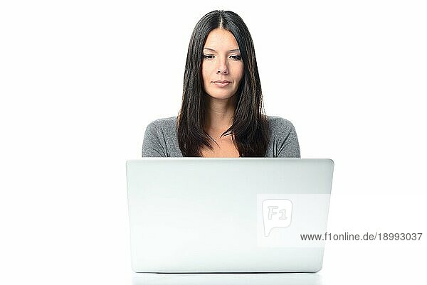 Freundliche junge Frau mit langen Haaren  die an ihrem Laptop arbeitet  vor weißem Hintergrund