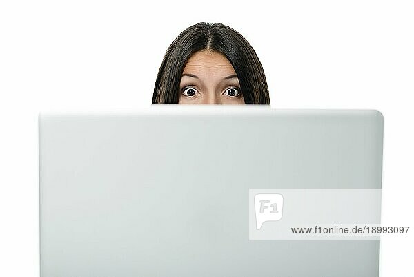 Geschäftsfrau  die mit offenem Mund und weit aufgerissenen Augen über ihren Computerbildschirm hinweg in die Kamera blickt  mit einem Blick voller Überraschung  Schock  Erstaunen und Bewunderung