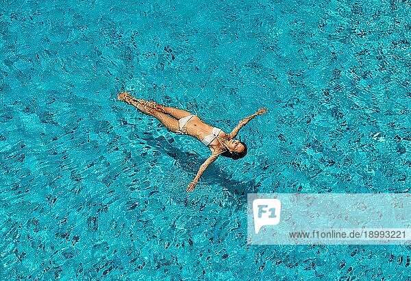 Draufsicht auf junge schlanke Frau in weißem Bikini entspannen und schwimmen in Infinity Pool. Sommerurlaub  Ruhe Konzept