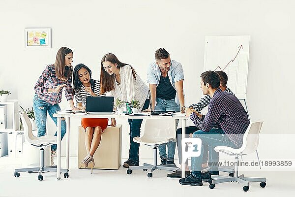 Lächelnde Gruppe junger Leute  die in einem kreativen Büro zusammenarbeiten und kommunizieren. Meeting  Teamworkkonzept erfolgreiches Team