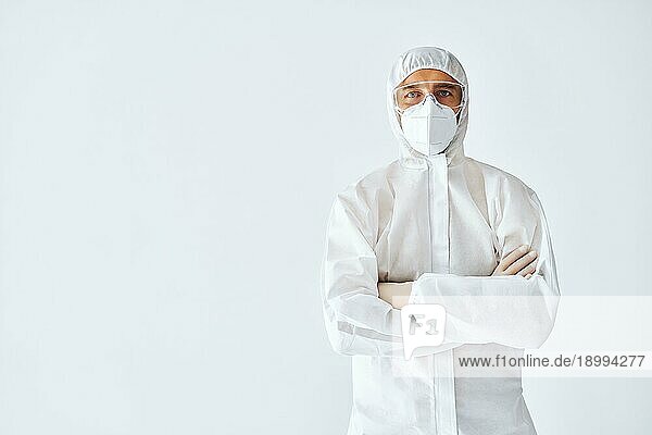 Selbstbewusster Arzt mit verschränkten Armen im medizinischen Schutzanzug mit Kopierraum auf weißem Hintergrund
