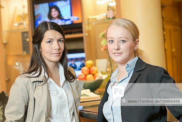 Zwei schöne stilvolle Frauen Freunde stehen zusammen in einem Luxus Zimmer Interieur Blick in die Kamera mit freundlichem Lächeln