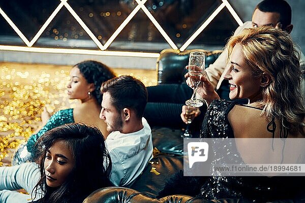 Diverse Gruppe von jungen Freunden abhängen und trinken Champagner im Nachtclub. Menschen genießen Party und haben Spaß Konzept