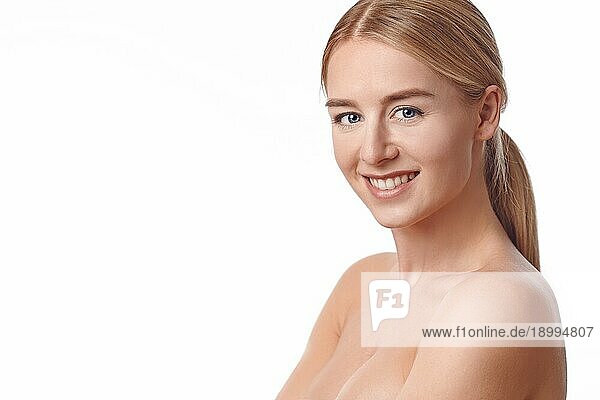 Schöne gesunde junge Frau voller Vitalität  die ihre Hände an ihre Wangen hält  um ihre Brüste zu schützen  während sie der Kamera ein strahlendes Lächeln schenkt