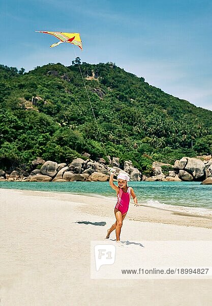 Happy hübsches Kind Mädchen mit einem Drachen läuft auf tropischen Strand im Sommer. Meer Spaß  Kindheit Konzept