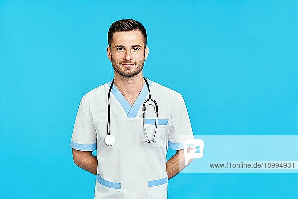 Porträt eines zuversichtlich lächelnden männlichen Arztes mit Stethoskop in medizinischer Uniform mit Kopierraum auf blauem Hintergrund