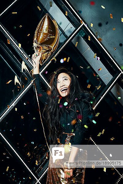 Hübsche glückliche asiatische Frau  die Spaß hat und auf einer Party tanzt und einen goldenen Ballon hält. Feiern Konzept