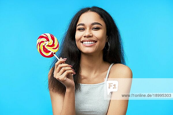 Happy schöne schwarze Frau mit bunten Lutscher auf blauem Hintergrund. Süßes Essen  Genießen  Spaß Konzept