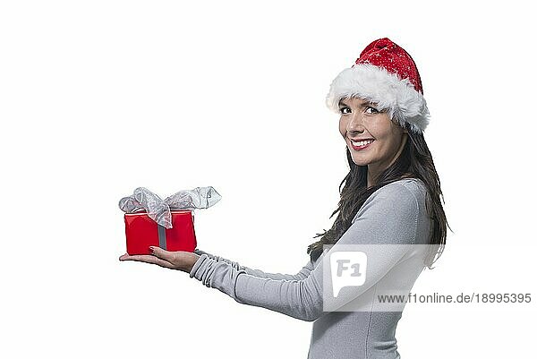 Hübsche junge Frau mit langen brünetten Haaren und einem schönen sanften Lächeln  die ein buntes rotes Geschenk für einen geliebten Menschen in der Hand hält