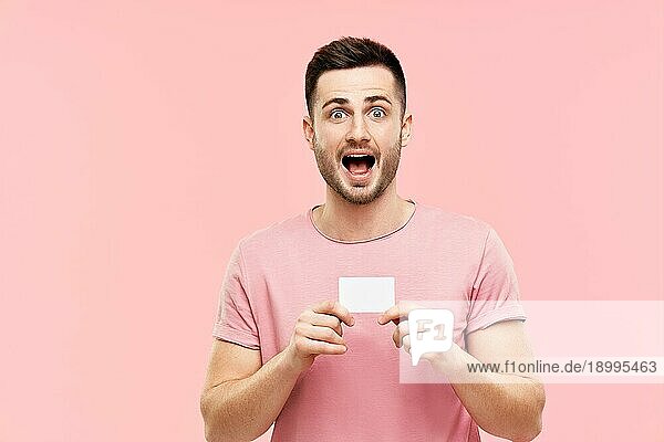 Erstaunt aufgeregt Mann mit offenem Mund hält Kreditkarte über rosa Hintergrund. wow  Emotionen  Erfolg  Gewinner Konzept