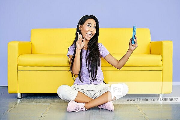 Lächelnde asiatische Frau Vlogger Aufnahme eines Videos auf Handy zeigt Sieg Zeichen. Technologie  Kommunikation Konzept