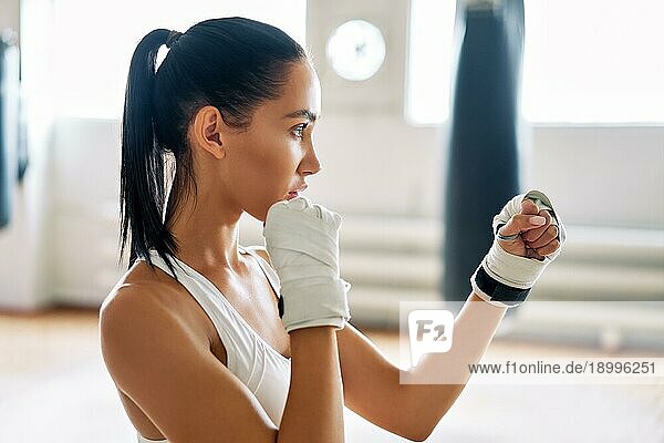 Junge Boxerin posiert in Kampfhaltung im Fitnessstudio. Sportliche Frau bereit für den Kampf