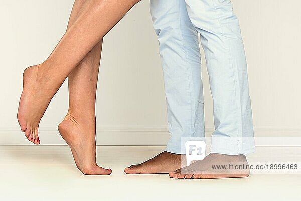 Nahaufnahme der Füße eines barfüßigen Mannes und einer Frau  die sich auf Zehenspitzen gegenüberstehen  was auf eine romantische Liaison schließen lässt
