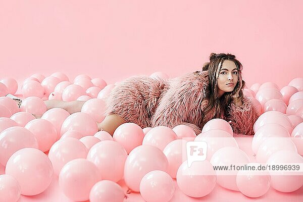 Mode Porträt der lächelnden hübsche Frau in vielen rosa Luftballons liegen. Entspannen  Party  Menschen Konzept