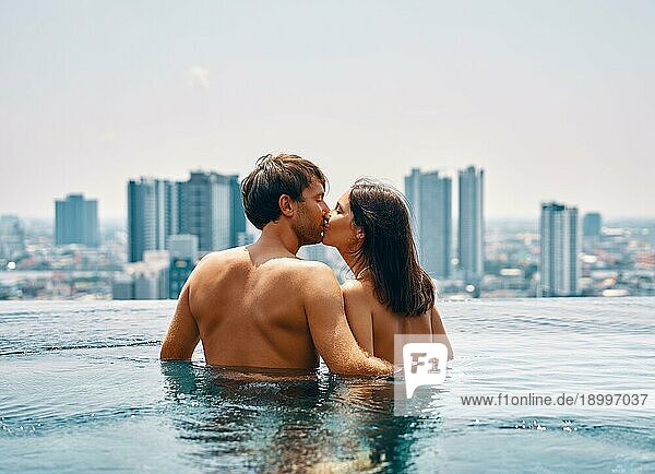 Junges glückliches Paar küsst sich im Schwimmbad im Sommerurlaub