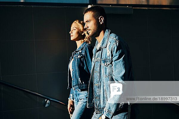 Modisches und selbstbewusstes junges Paar in Denim Jeans gehen nach oben in Richtung Sonne. Liebe  Beziehung und Erfolg Konzept