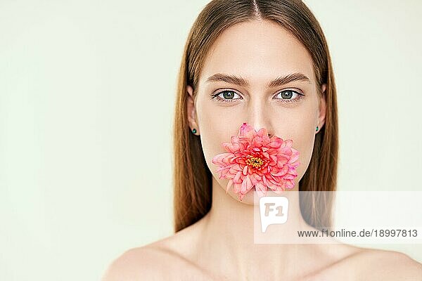 Close up Porträt der schönen jungen Frau hält Blume im Mund. Weibliche Schönheit  Spa  saubere Haut Konzept
