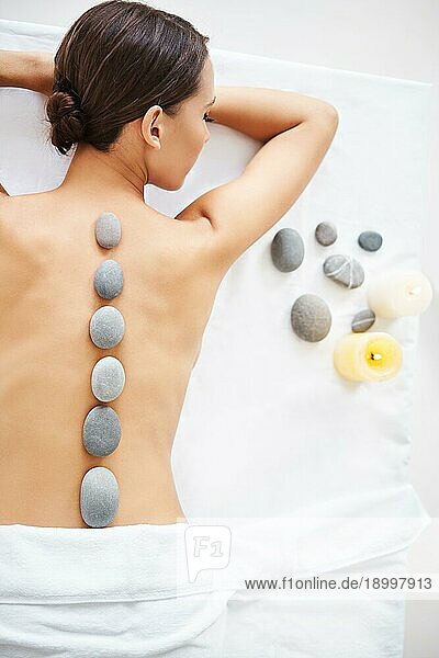 Schöne junge Frau entspannt sich bei einer Hot Stone Massage. Therapie  Schönheitsbehandlung Konzept