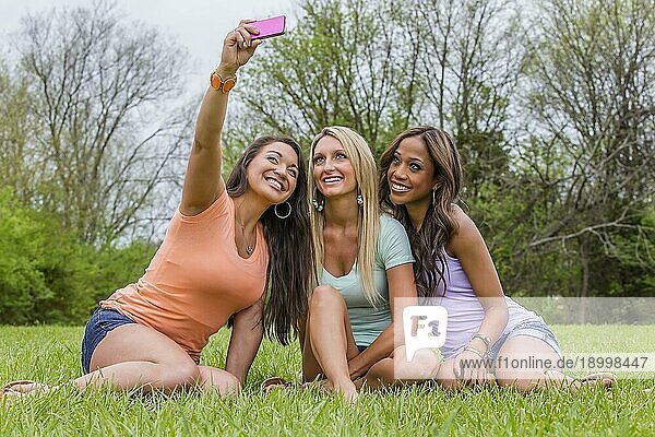 Drei junge Frauen machen Selfies und genießen einen Tag im Park