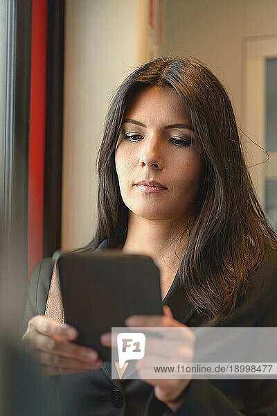 Ein Porträt der attraktiven brünetten Frau  die im Zug ein Tablet benutzt  während sie von der Arbeit pendelt