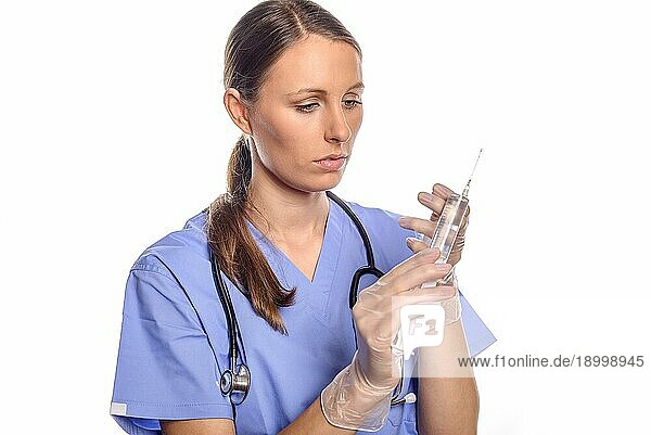 Ernste attraktive Krankenschwester oder Ärztin  die eine große Injektionsspritze hält  während sie überlegt  wie sie eine so große Dosis an Medikamenten am besten verabreichen kann  vor weißem Hintergrund