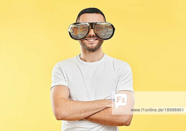 Junger Mann mit lustiger Partybrille auf gelbem Hintergrund. Spaß Konzept