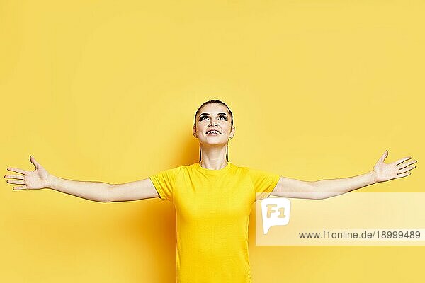 Glückliche Freiheit junge Frau mit erhobenen Händen Blick nach oben auf Kopie Raum über gelben Hintergrund Ausdruck Konzept