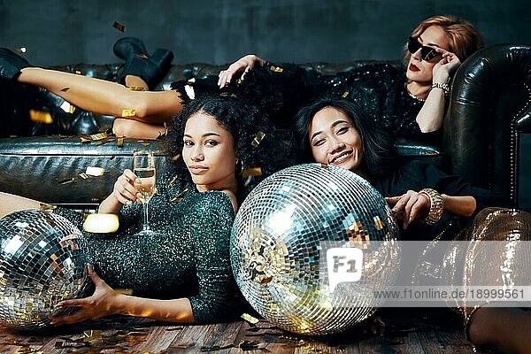 Verrückte Party. Hübsche multiethnische junge Frauen entspannt nach der Party  liegen auf dem Boden und Sofa. Feiern Konzept