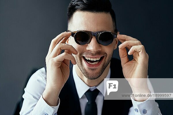 Glücklicher lachender Mann mit Retro Sonnenbrille auf schwarzem Hintergrund. Spaß Konzept