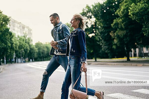 Junges glückliches Paar läuft über den Zebrastreifen auf der Straße Spaß  Wandern  Dating Konzept