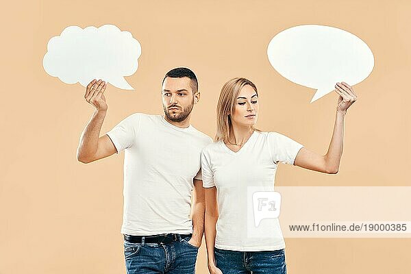 Upset Frau und Mann halten Papier Gedankenblasen über beige Hintergrund. Beziehung Konzept