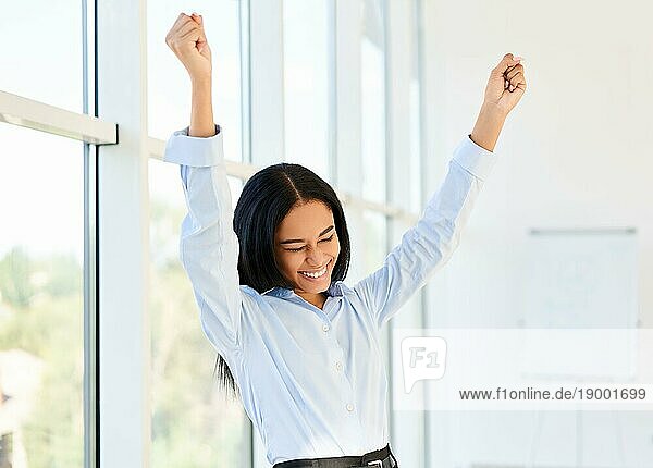 Porträt einer glücklichen  aufgeregten schwarzen Geschäftsfrau mit erhobenen Armen  die ihren Erfolg in einem modernen  kreativen Büro feiert