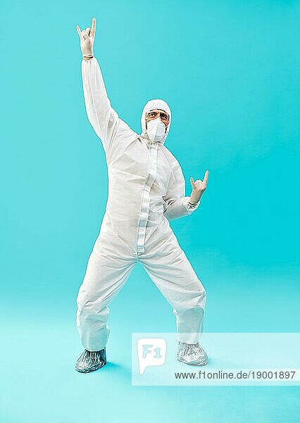 Full lenght Porträt von glücklichen Arzt in PSA Anzug feiert seinen Erfolg mit Sieger Geste und Hände hoch auf blauem Hintergrund. Sieg  Triumph und Emotionen Konzept