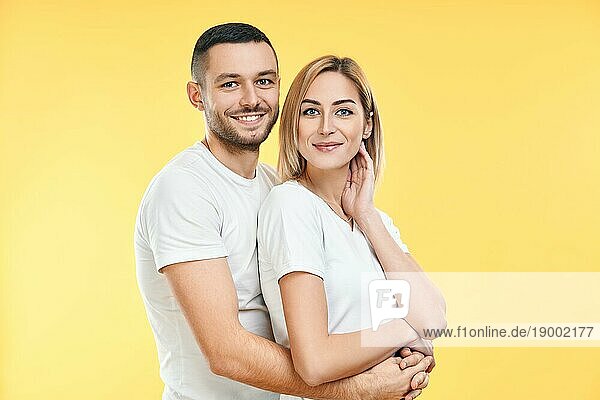 Junges glückliches Paar  das sich auf gelbem Hintergrund umarmt. Beziehung Konzept