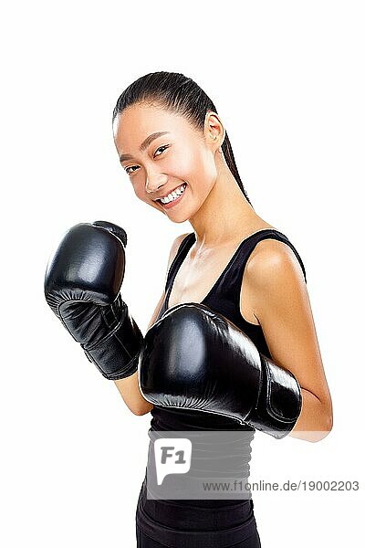 Porträt einer lächelnden  sportlichen Frau in schwarzen Boxhandschuhen  die in die Kamera schaut  auf weißem Hintergrund. Sport Konzept