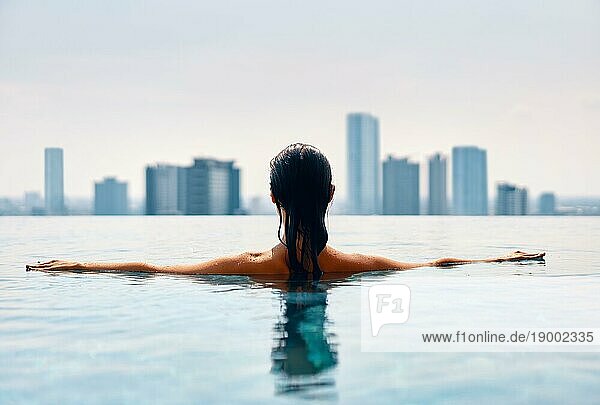 Urlaub genießen Rückenansicht einer jungen Frau beim Schwimmen im Swimmingpool auf dem Dach