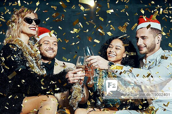 Multiethnische glückliche Freunde stoßen mit Champagner an  feiern Weihnachten oder Neujahr  gratulieren sich gegenseitig und genießen die Party. Feiern und Prost Konzept