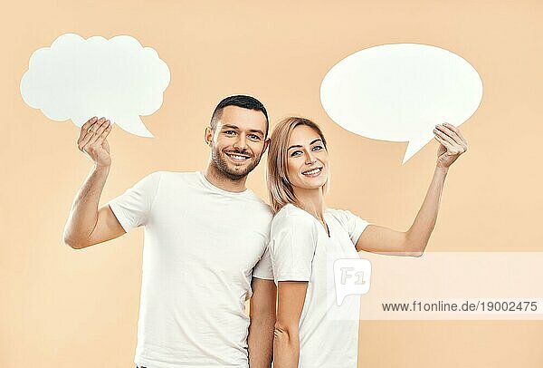 Lächelnde Frau und Mann halten Papier Gedankenblasen über beige Hintergrund. Beziehung Konzept
