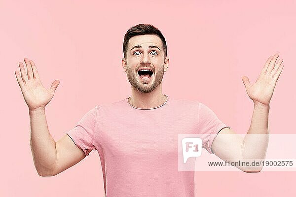 Überrascht aufgeregt Mann Porträt mit erhobenen Armen über rosa Hintergrund. Emotionen  Erfolg  Gewinner Konzept