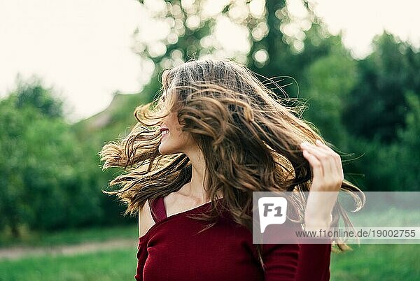 Junge glückliche Frau mit flatternden Haaren haben Spaß im Freien auf grünen Sommer Natur Hintergrund. Weibliche Schönheit Konzept