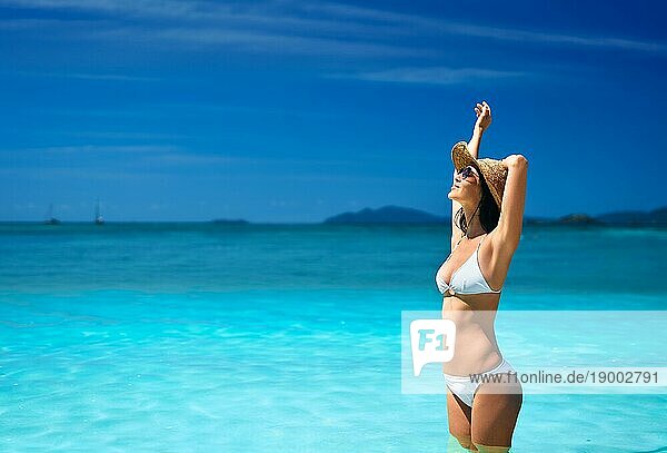 Schöne sexy Frau in weißem Bikini und Strohhut entspannen in türkisfarbenen Meerwasser auf tropischen Strand mit Kopie Raum im Urlaub. Sommerträume  Reisekonzept