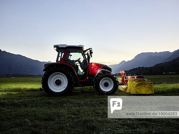 Tractor on grass field at dusk