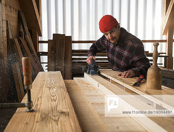 Carpenter working with hand planner at workshop